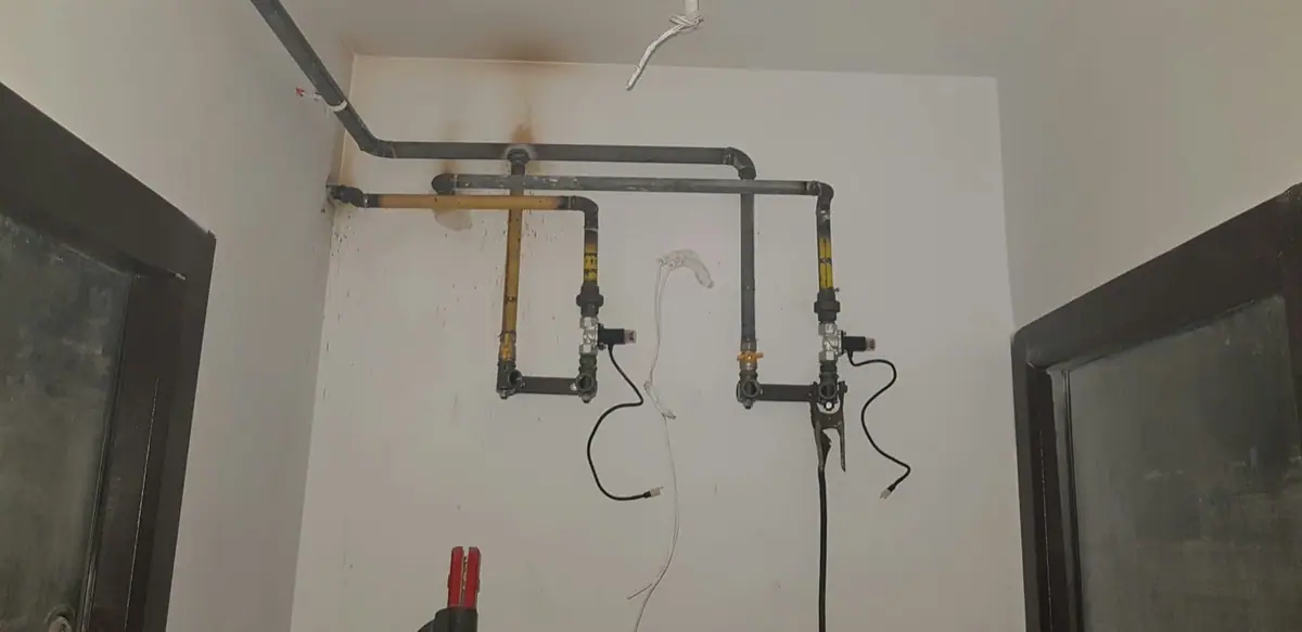 Țevi galbene și gri de instalație de gaz, cu robineți montați pe perete