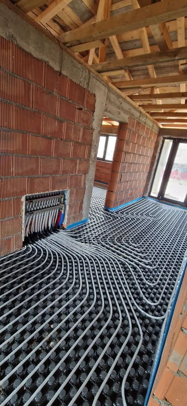 Colector montat în perete și țevi de încălzire în pardoseală, într-o casă cu structură de lemn la acoperiș